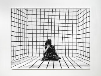 Photograph of figure wrapped completely in black tape, with another figure behind it and reaching its arm around, sitting in a room with a black grid marked out on floor and walls