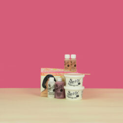 Color photographic still life of Black hair supplies arranged on a cream surface and against a pink background