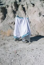 Color photograph of one pair of white basketball shorts standing in a canyon